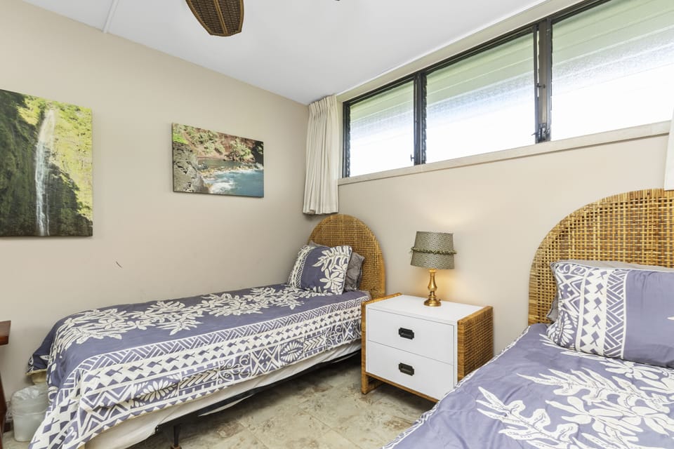 Step into your peaceful twin bedroom with rattan headboards, nature-inspired artwork, and soft natural light filtering through the windows—your serene island retreat awaits.