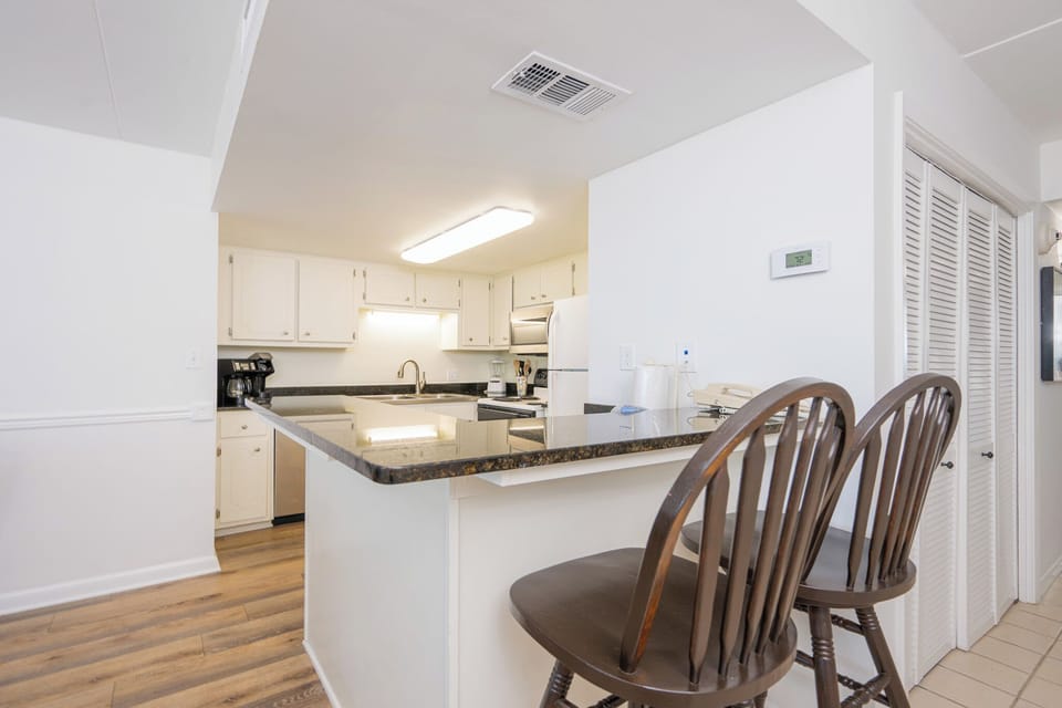 This dining area features a round wooden table and opens to a well-equipped kitchen, perfect for family meals