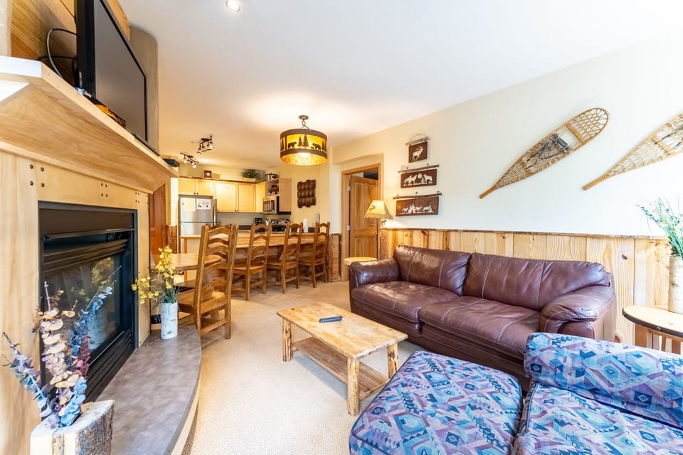 Cozy up by the fireplace in this spacious living area with leather seating, rustic décor, and mountain charm throughout.