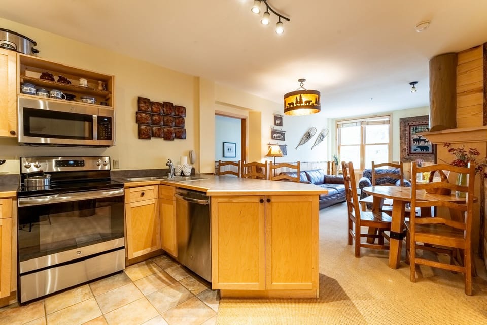 Your fully equipped kitchen flows seamlessly into the cozy dining area, perfect for preparing meals and gathering together after mountain adventures.