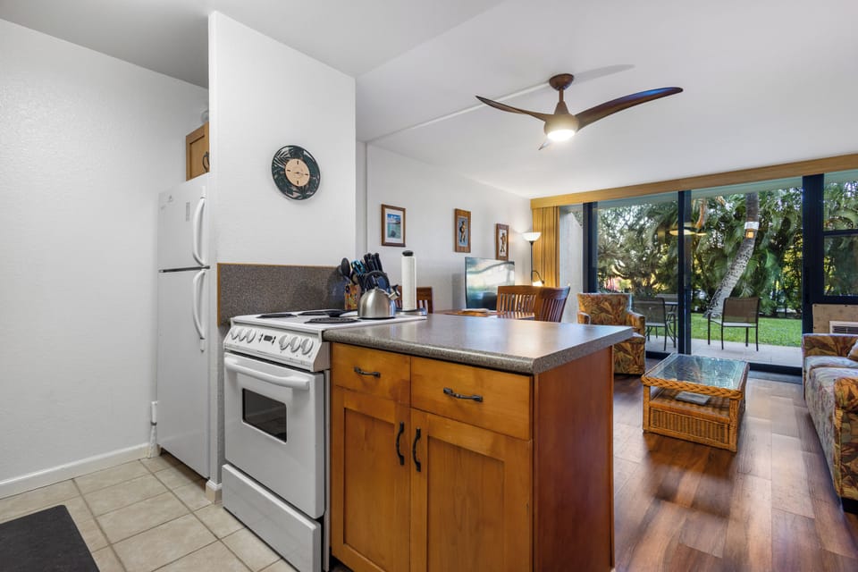 Step into your home away from home with a fully equipped kitchen, inviting living space, and lush garden views through sliding glass doors. Your perfect island getaway awaits.