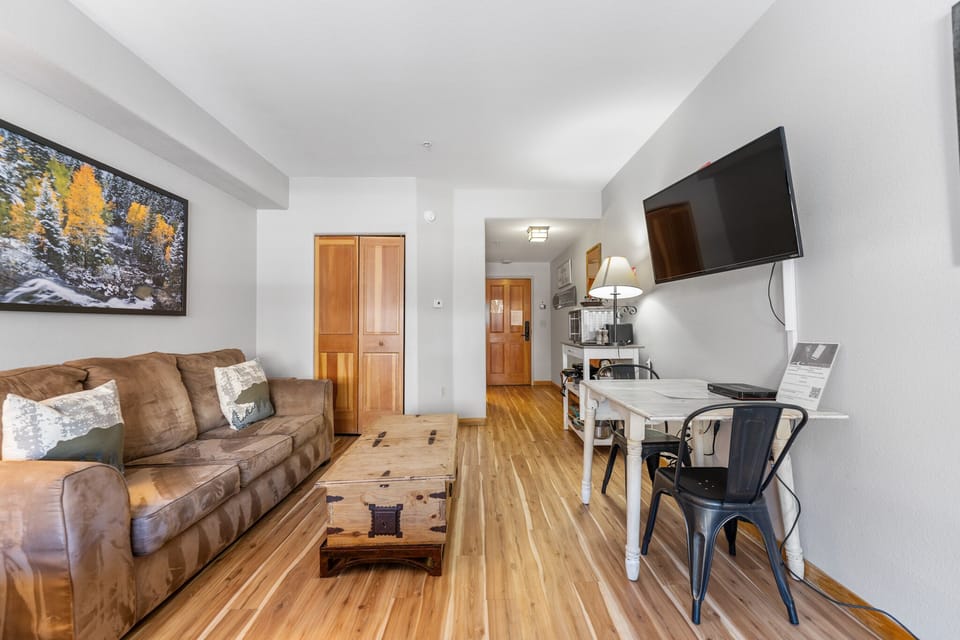 Relax in your bright, open-plan space with rich wood floors, cozy leather sofa, and modern kitchen—perfect for unwinding after your adventures.