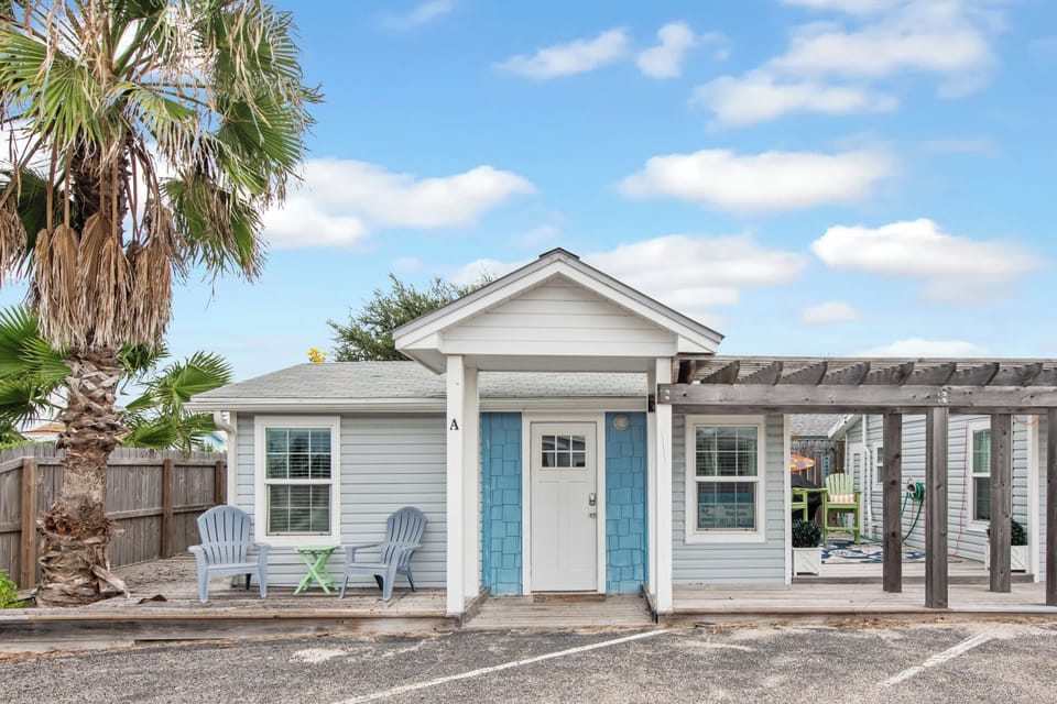 Charming coastal cottage with turquoise shutters and palm trees creates a perfect beach getaway retreat.