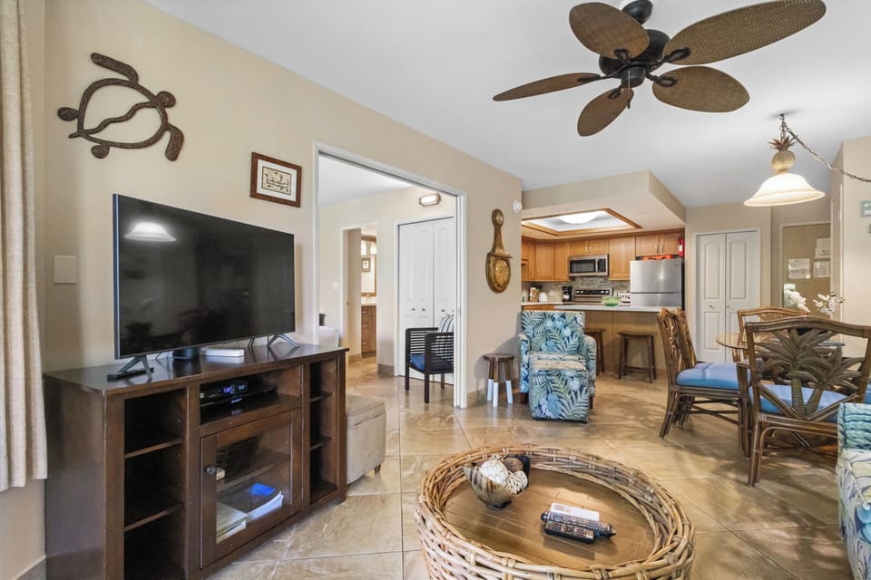 Relax in your tropical-themed living space with comfortable seating, entertainment center, and open kitchen perfect for your island getaway.