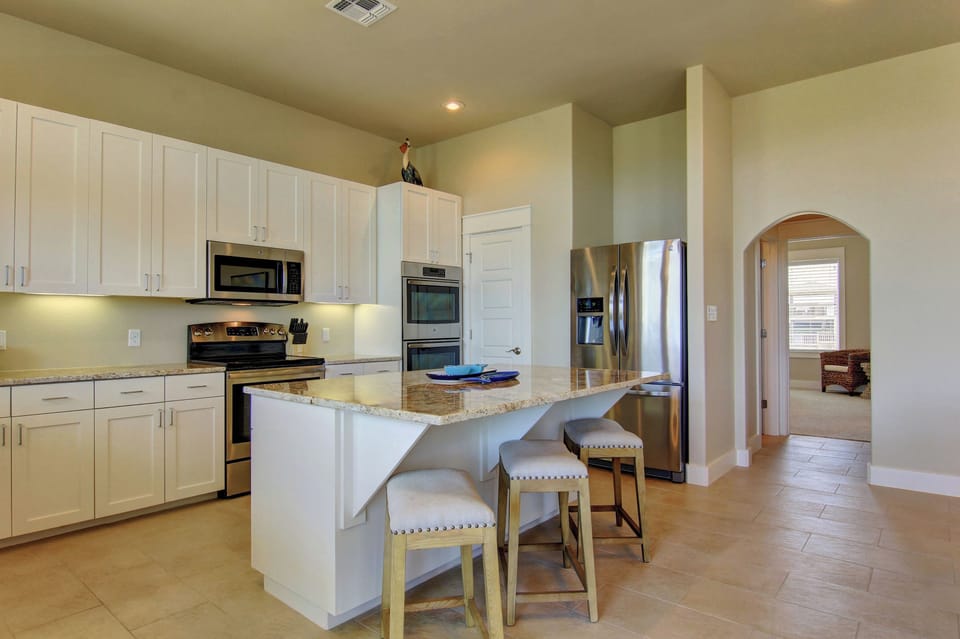 Cook your favorite meals in this bright, fully-equipped kitchen featuring granite countertops, stainless steel appliances, and a breakfast bar.