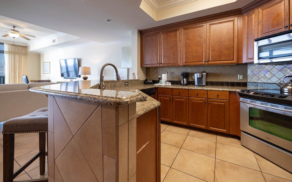 This kitchen features rich wooden cabinets, stainless appliances, granite countertops, a coffee maker and Keurig