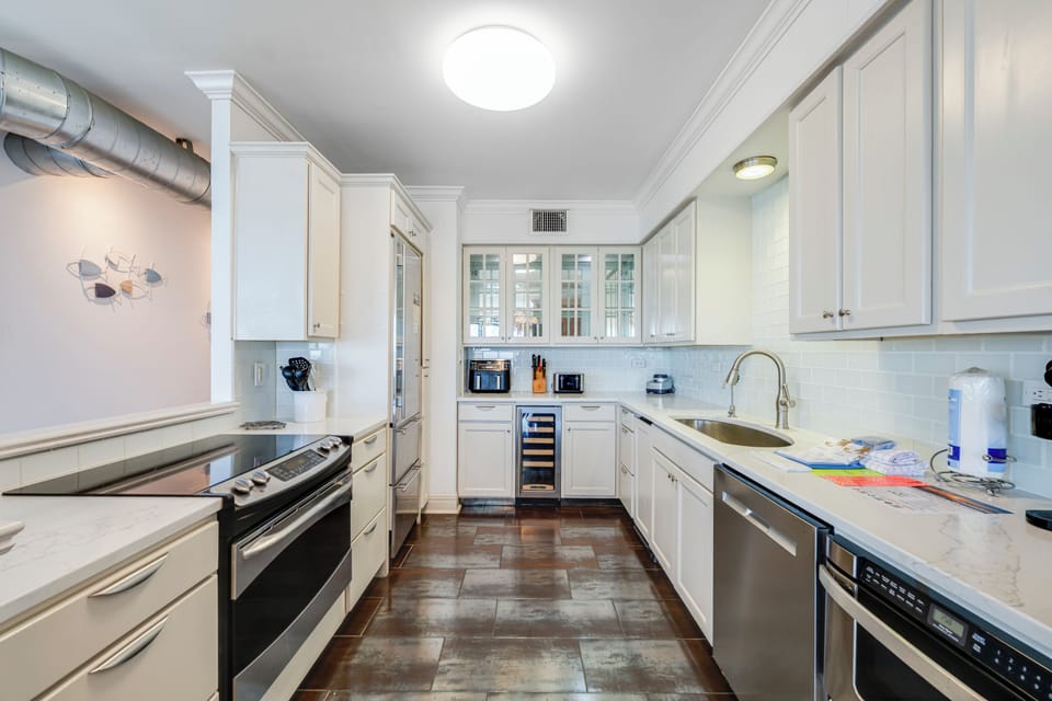 Your gourmet kitchen awaits with gleaming white cabinetry, premium appliances, and marble countertops perfect for creating memorable meals together.