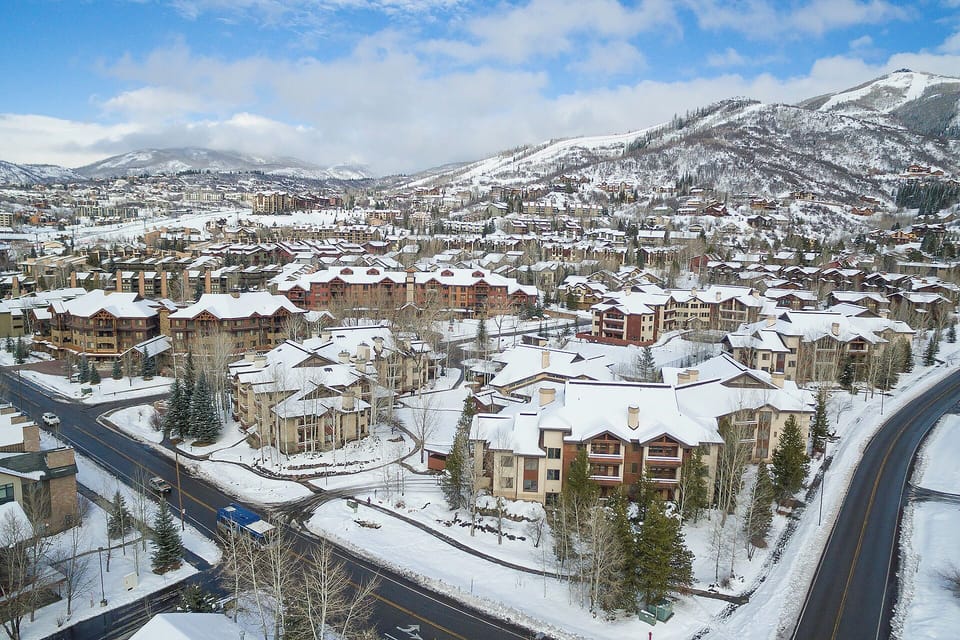 Mountain village nestled in snowy peaks with charming buildings and winter roads winding through the valley.
