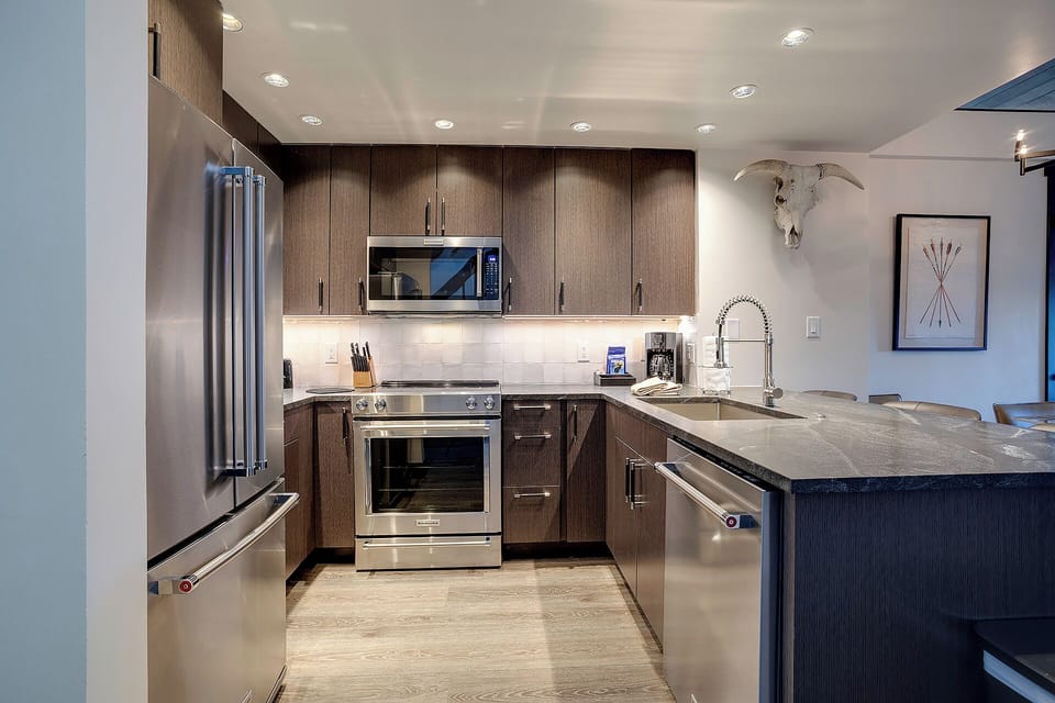 Your sleek kitchen features premium appliances, warm wood cabinetry, and granite countertops—perfect for preparing memorable meals during your stay.