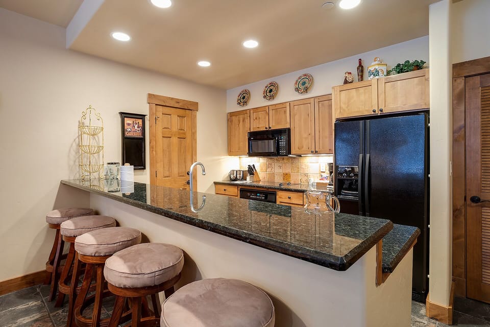 Your gourmet kitchen features granite counters and breakfast bar seating, perfect for preparing meals and gathering with loved ones in rustic elegance.