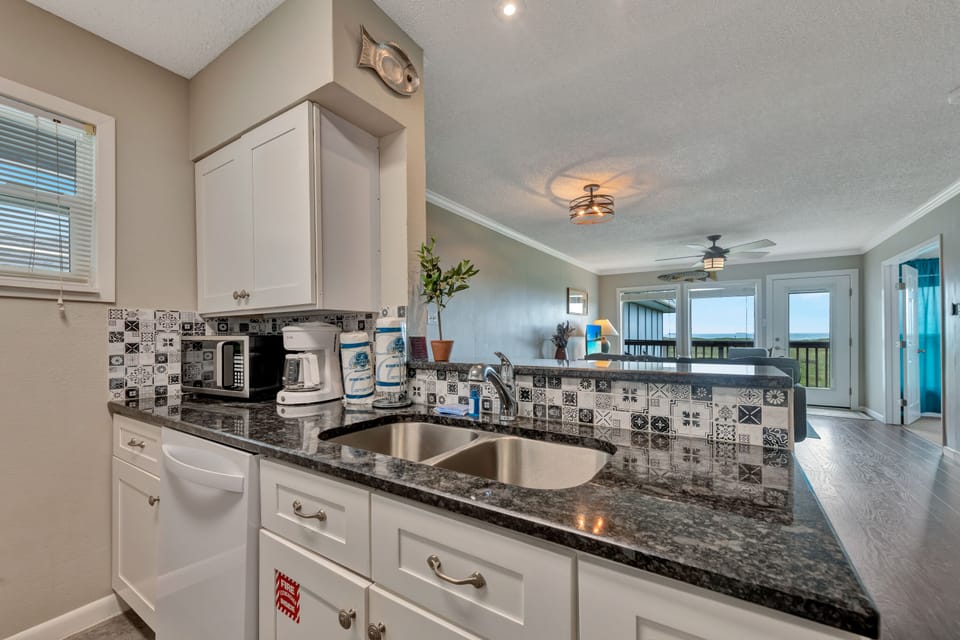 Your stylish kitchen features granite counters, patterned backsplash, and stainless appliances—perfect for preparing meals while enjoying stunning views.