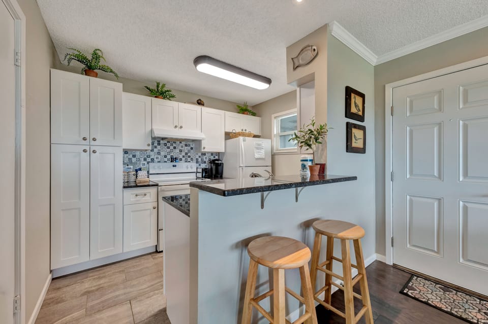 Your fully equipped kitchen features white cabinets, granite counters, and a convenient breakfast bar for morning coffee or casual meals.
