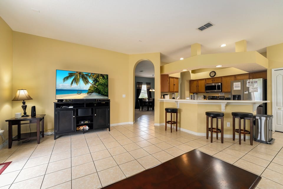 Seating area showing TV and Kitchen with seating for 3 at the breakfast bar