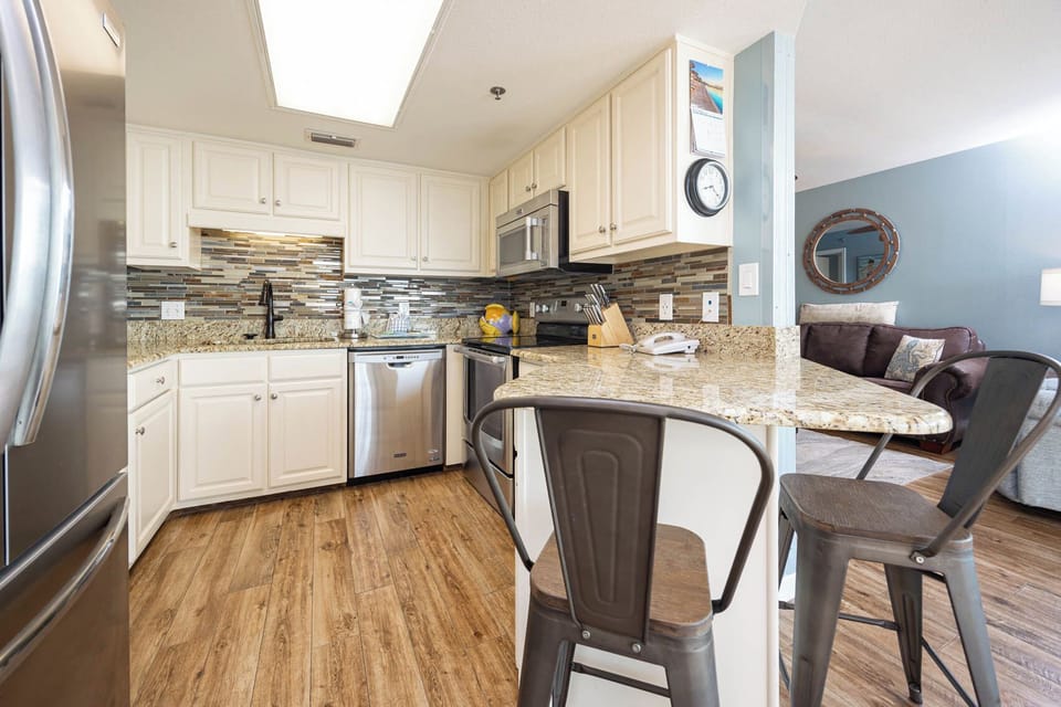 Bright kitchen featuring granite countertops, modern cabinetry, and a breakfast bar with stylish seating for casual dining