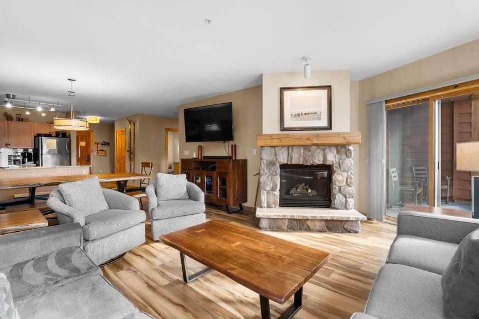 Cozy up by your stone fireplace in this warm living space, where comfortable seating and mountain charm create the perfect retreat.