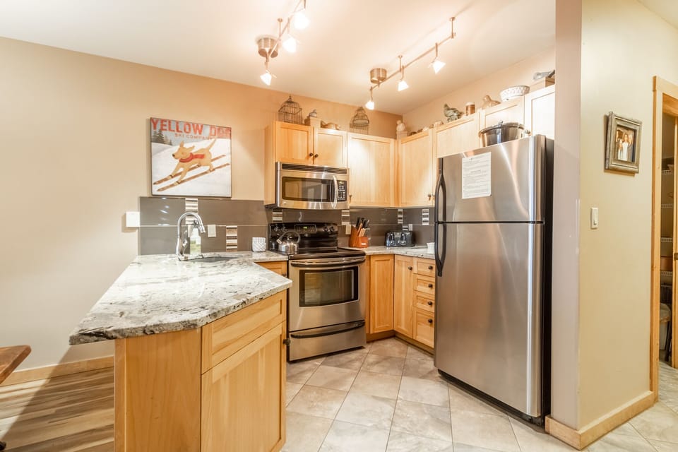 Your fully equipped kitchen features granite counters, stainless appliances, and warm wood cabinets—perfect for preparing memorable meals during your mountain getaway.