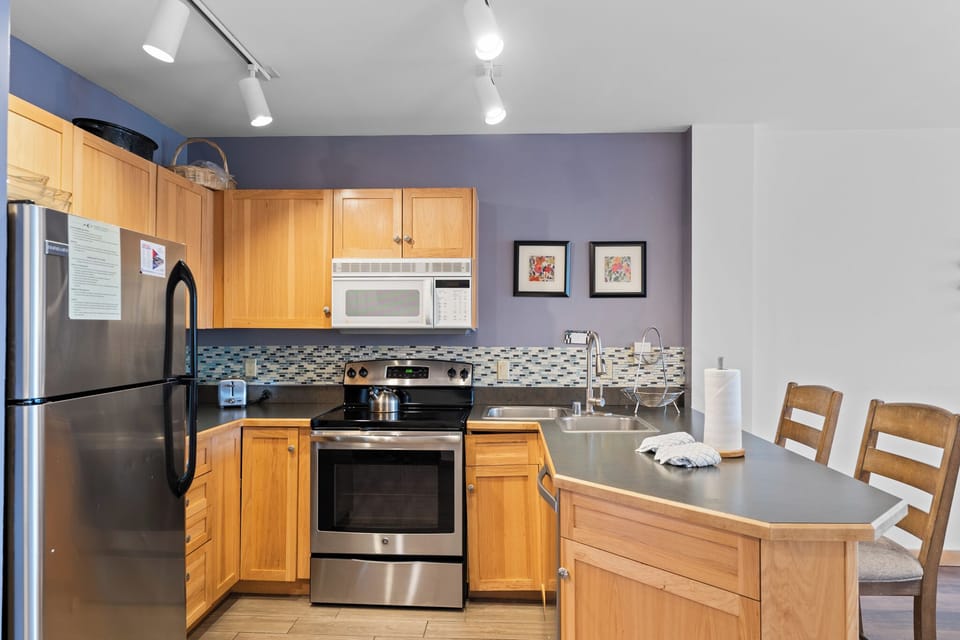 Your fully equipped kitchen features warm wood cabinets, stainless steel appliances, and a convenient breakfast bar for casual dining.