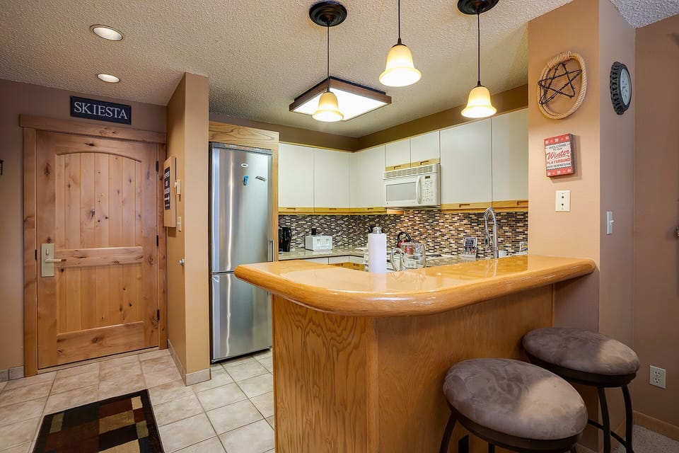 Your fully-equipped kitchen features warm wood finishes, modern appliances, and a breakfast bar perfect for morning coffee or casual meals.