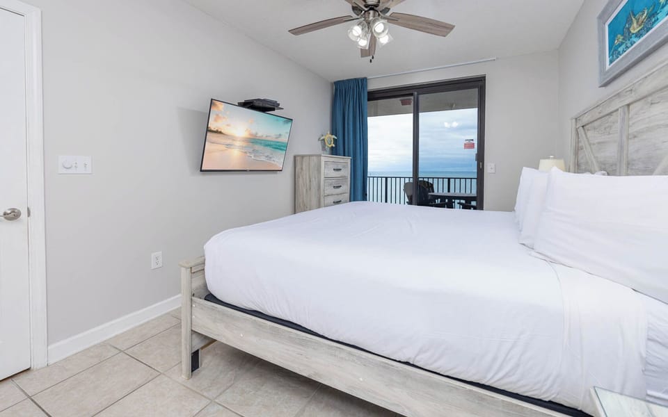 Unwind in this inviting master bedroom with a king bed, flat-screen TV, and a view of the beach from the balcony
