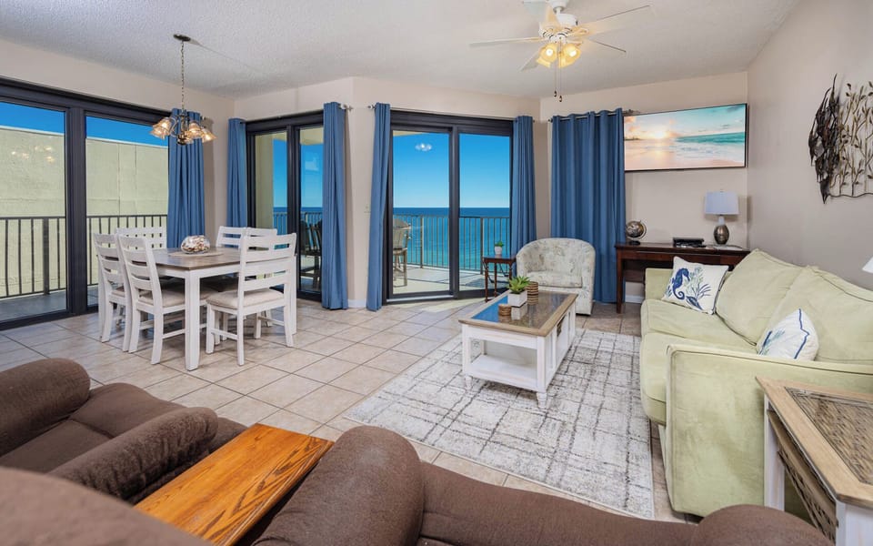 Bright living area featuring a cozy sofa with queen sleeper, dining table, and panoramic views of the beach