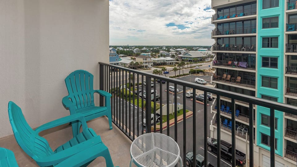 This balcony features turquoise chairs and a view of charming coastal homes, perfect for relaxing and enjoying the scenery