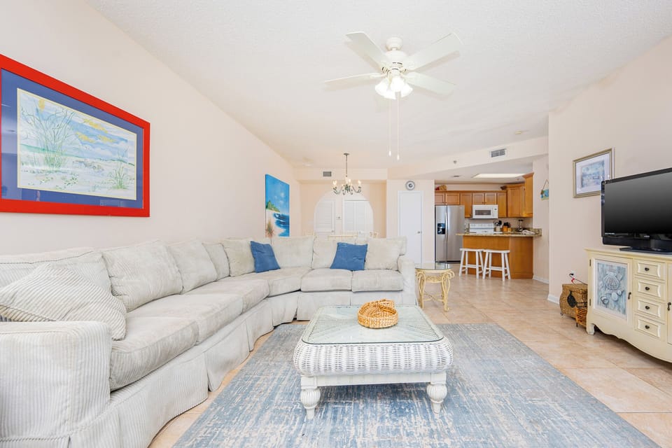 The airy living room features a large sectional sofa with queen sleeper, a coffee table, and a view of the dining area