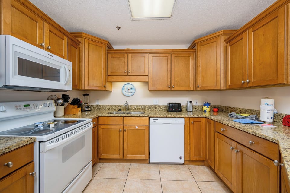 The kitchen features warm wooden cabinets, marbled countertops, and a convenient breakfast bar area