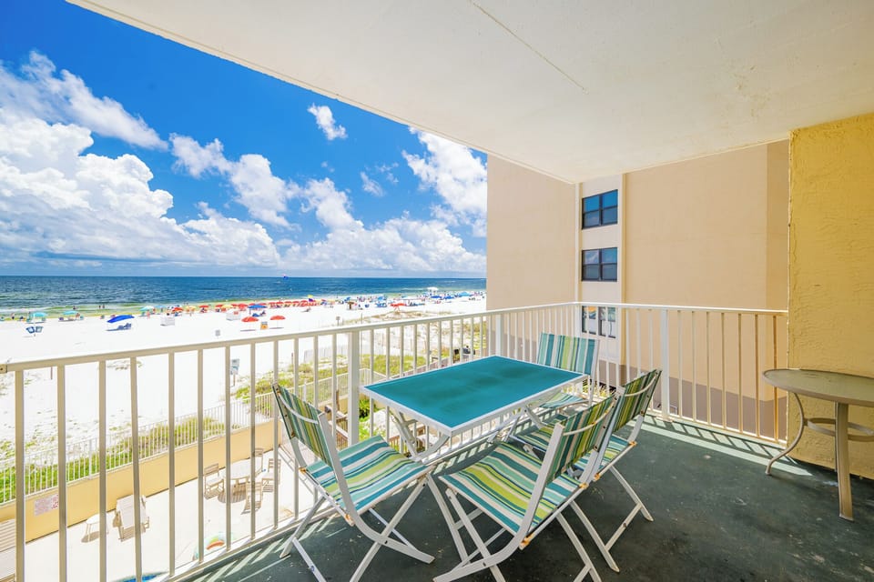 Enjoy a beachfront view from the balcony, featuring a table and chairs with colorful stripes for relaxation