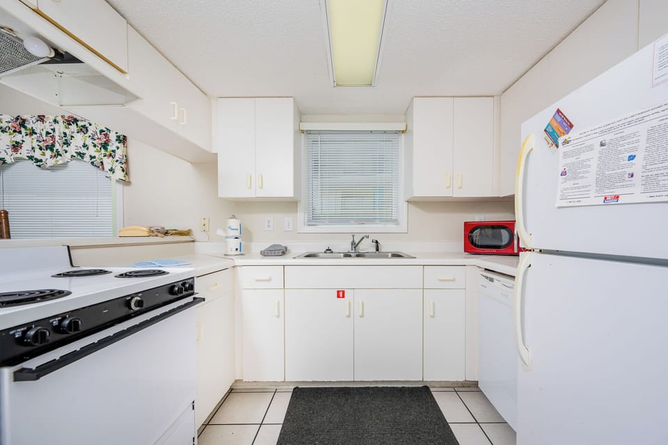 This kitchen features white cabinetry, a stove, and a window providing a bright, cheerful atmosphere for meal preparation