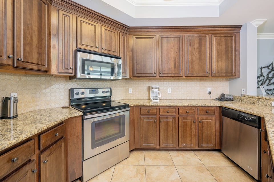 Modern kitchen with stainless appliances, granite countertops, and warm wood cabinetry, perfect for culinary adventures