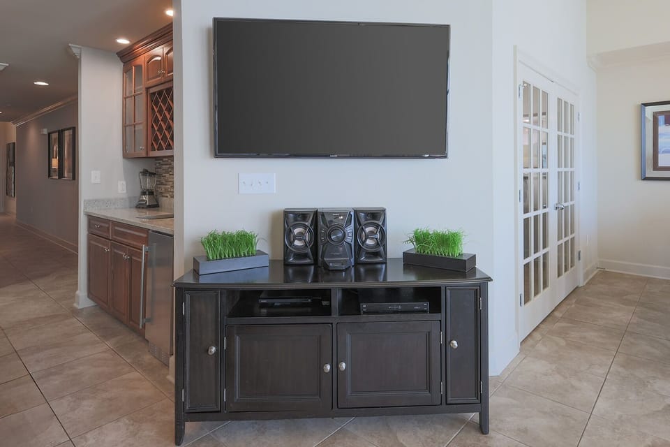 The living space features a large TV above a stylish cabinet with speakers, perfect for relaxing evenings