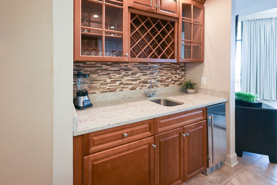 The wet bar features elegant cabinetry, a sleek countertop, and a blender, perfect for mixing drinks while enjoying the view