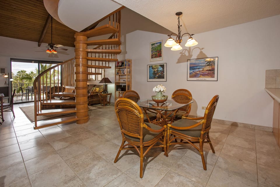 Gather around your tropical-inspired dining table beneath the warm glow of pendant lighting. The open floor plan connects you to ocean breezes and island views through glass doors.