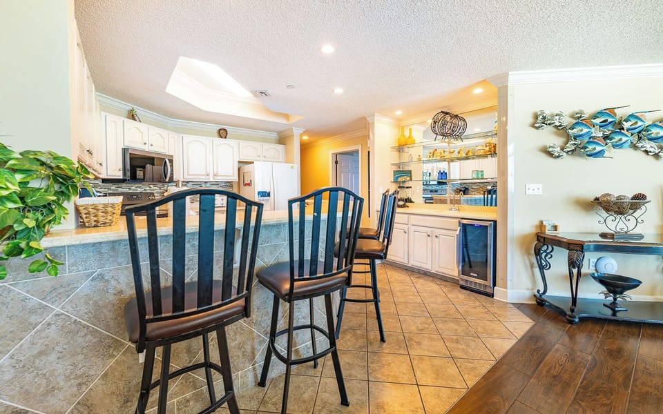 A breakfast bar with tall chairs invites you to sip drinks and chat in the bright kitchen space