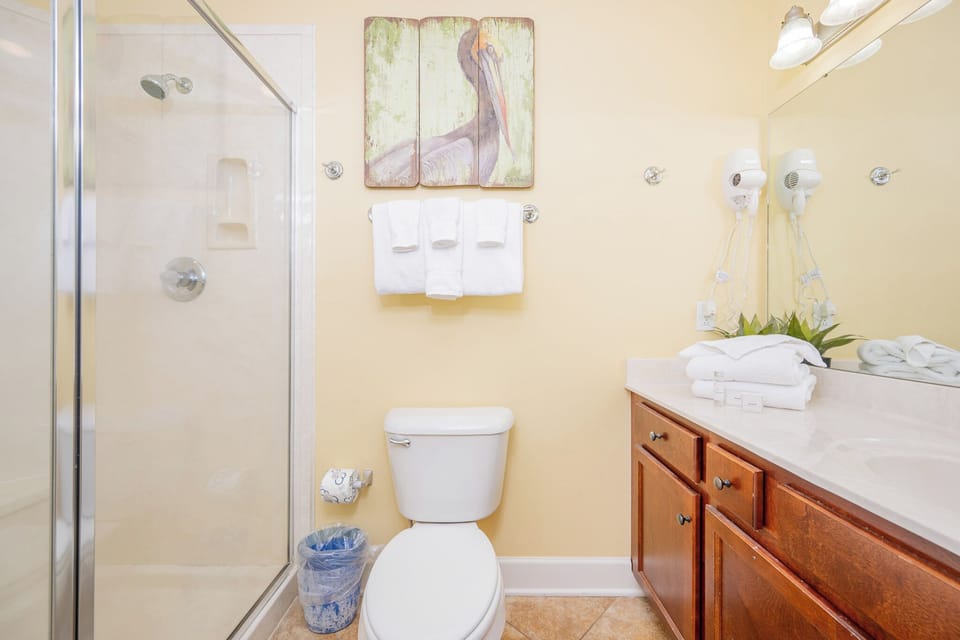 Inviting guest bathroom featuring a walk-in shower, fresh towels, and stylish wooden cabinetry for a relaxing stay