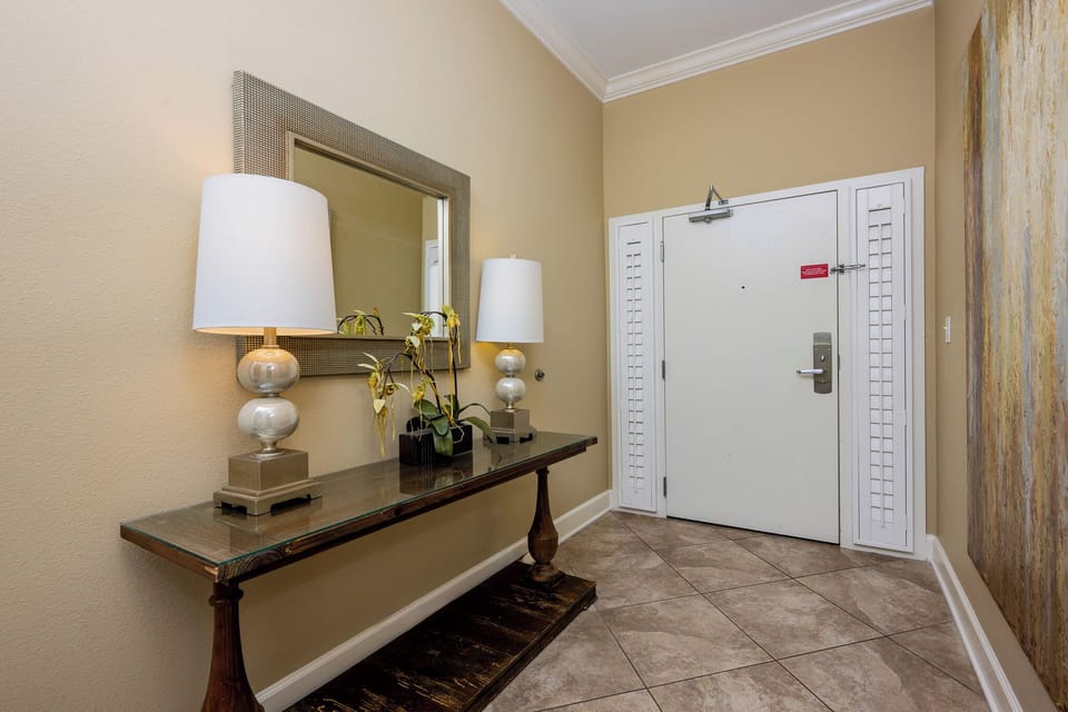 This welcoming entryway features a stylish table, elegant lamps, and a large mirror, creating a bright first impression