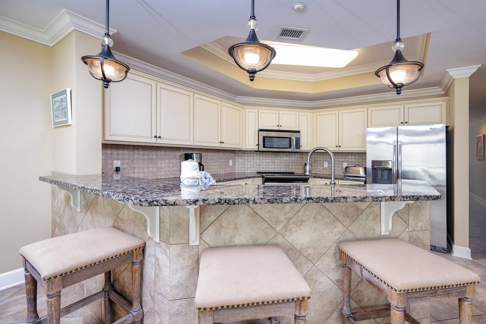 This stylish kitchen features elegant cabinetry, stainless appliances, sleek countertops, and modern lighting and tile work