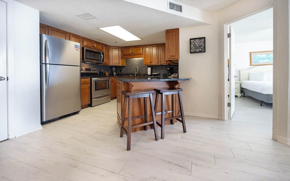 The modern kitchen features dark countertops, wooden cabinetry, and a breakfast bar with stools