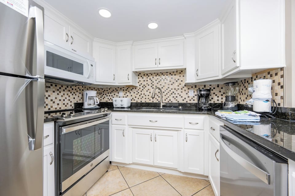 This kitchen features stainless appliances, granite countertops, and a stylish mosaic backsplash for delightful cooking