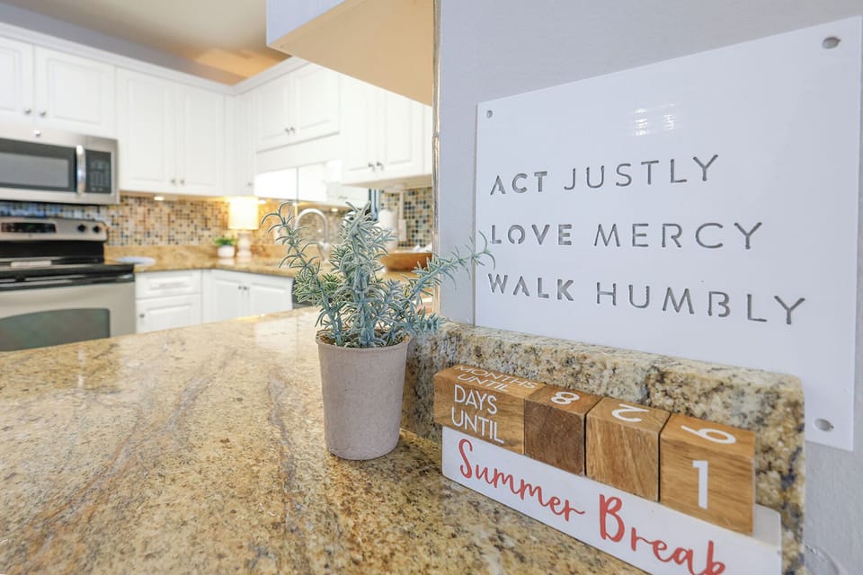 The modern kitchen features granite countertops, white cabinetry, and decorative accents, creating a welcoming atmosphere
