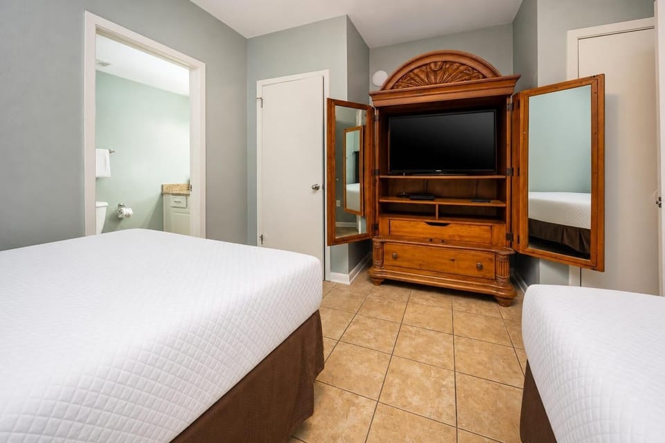 Enjoy restful nights in this inviting guest bedroom with two double beds, a TV, and easy access to the adjoining bathroom