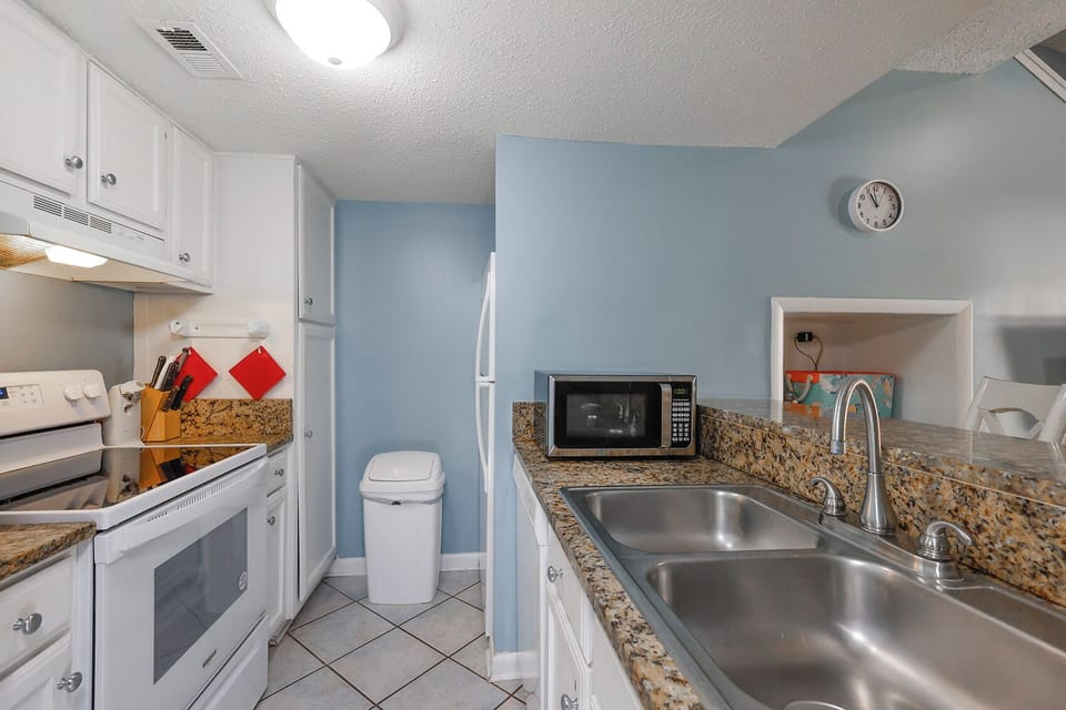 The kitchen features white cabinets, granite countertops, and modern appliances, perfect for meal preparation