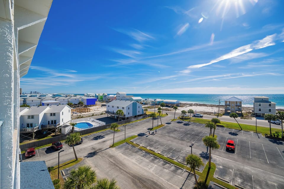 Gaze at the shimmering coast from your balcony, savoring the bright skies and tranquil vibe
