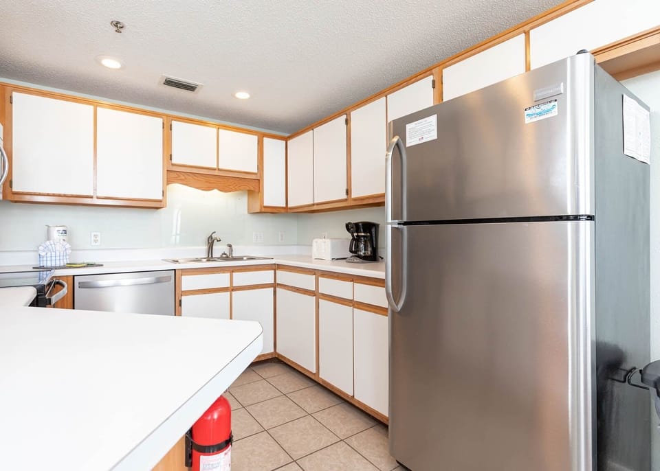The light cabinetry complements the spacious layout, featuring a breakfast bar and stainless appliances