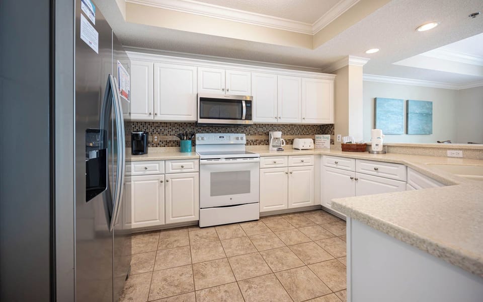 Prepare meals in this kitchen featuring white and stainless appliances, ample counter space, and a coffee corner