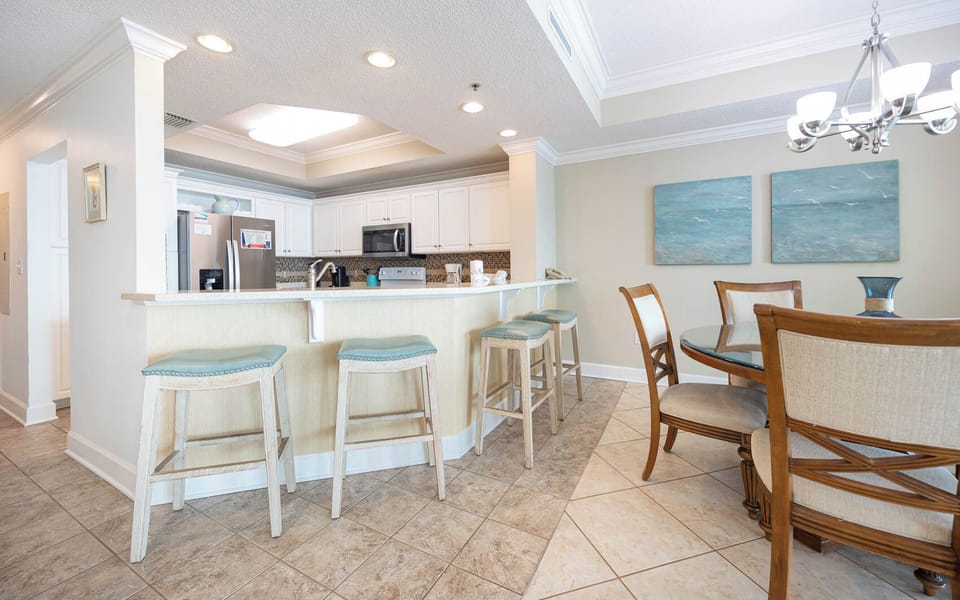 Gather around the breakfast bar with stylish stools, or enjoy meals at the round dining table beside serene artwork