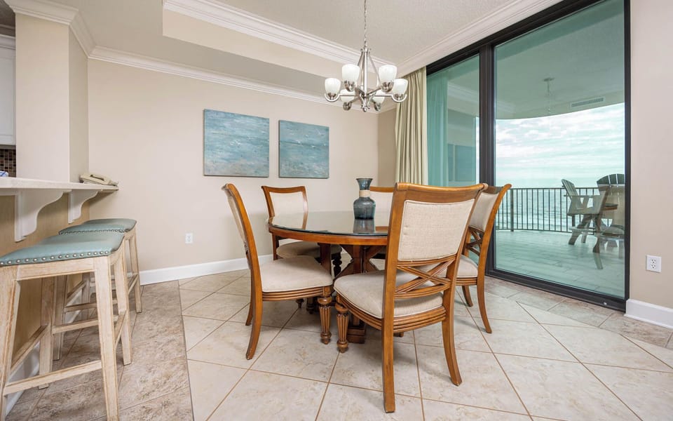 Dine at this round table surrounded by comfortable chairs, with a view through large glass doors to the balcony