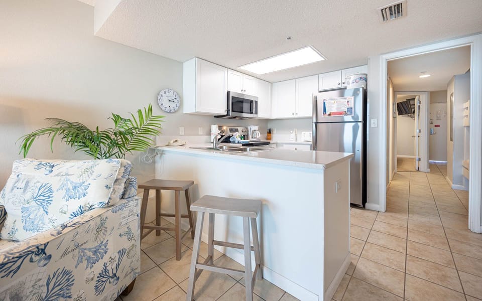 Prepare meals in the open kitchen with stainless appliances, bar seating, and coastal decor for a relaxing stay