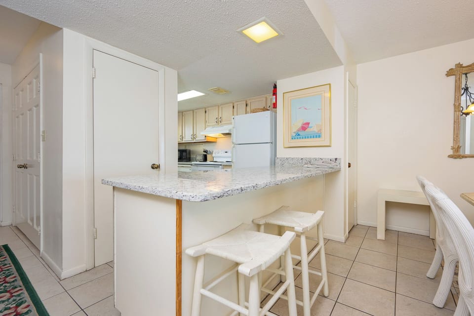 The kitchen features a wooden breakfast bar, white cabinetry, and a cozy seating area, perfect for casual dining