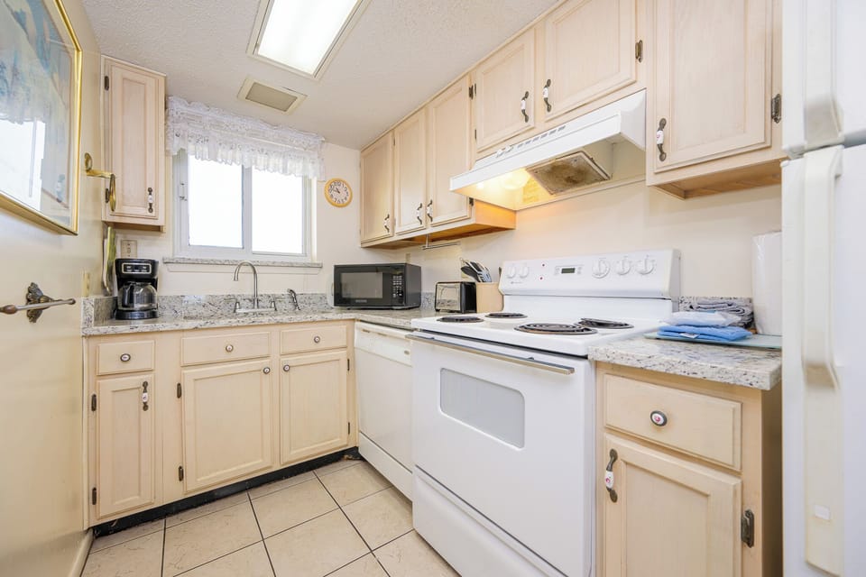 This kitchen features light cabinetry, essential appliances, and a cozy atmosphere perfect for meal preparation